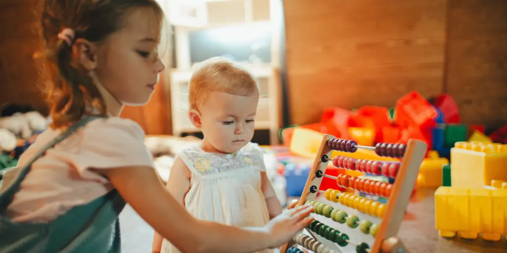 Kinder spielen mit einem Abakus in einem Raum voller Spielzeugklötze.